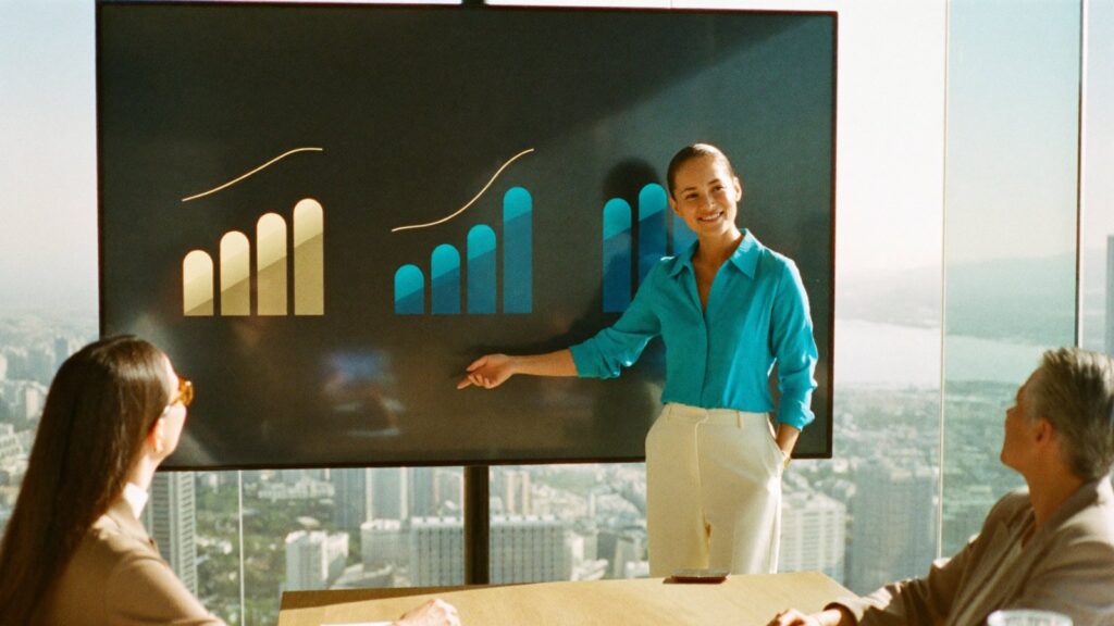 A presenter points at bar charts on a meeting-room screen while a QROPS pension transfer is talked through.