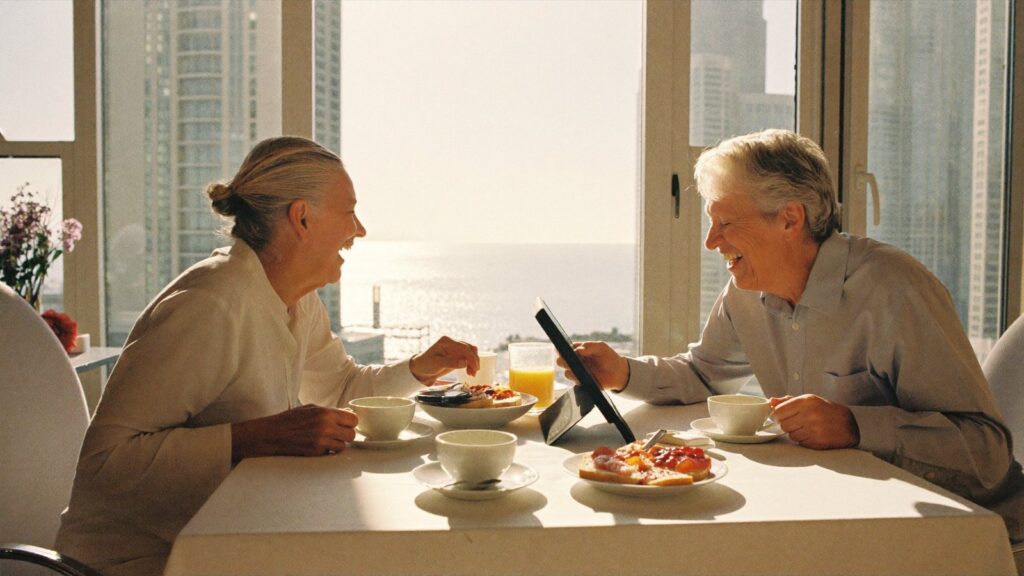 A retired couple share breakfast by a bright Dubai window, reading whether a UK State Pension is frozen once you retire abroad.
